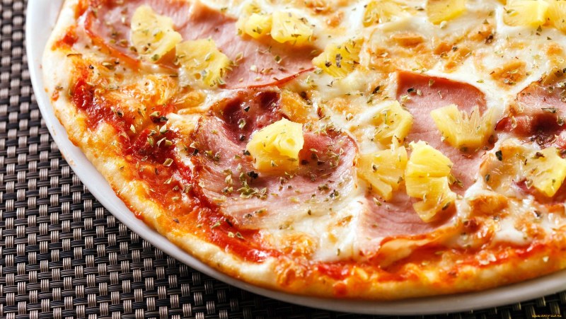 Пицца с ветчиной и ананасами на белом фоне