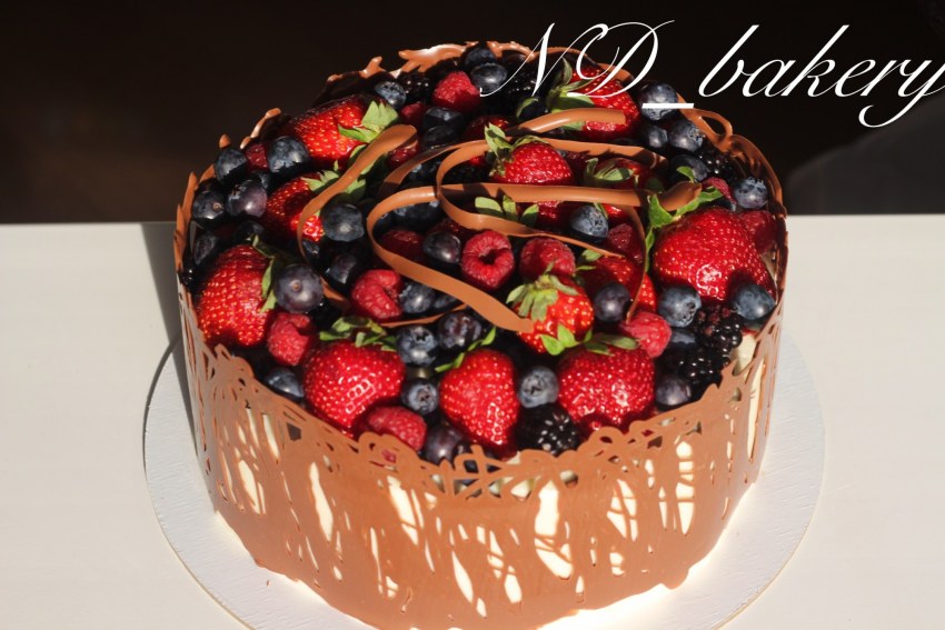 Торт бисквитный украшен шоколадным кремом и фруктами фото