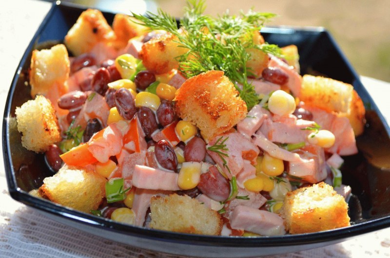 Салат с фасолью и сухариками и колбасой с помидорами с кукурузой